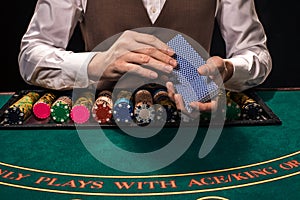 Close up of holdem dealer with playing cards and chips on green table