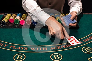 Close up of holdem dealer with playing cards and chips on green table