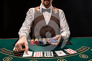 Close up of holdem dealer with playing cards and chips on green table