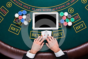 Casino, online gambling, technology and people concept - close up of poker player with playing cards