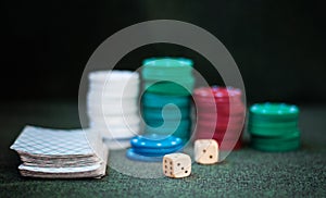 Casino poker chips stack with playing cards, dice on green felt background