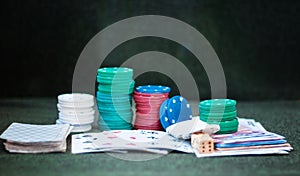 Casino poker chips stack with playing cards, dice and money on green felt background