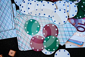 Casino poker chips stack with playing cards, dice and money on green felt background