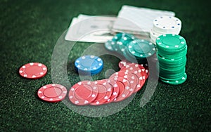 Casino poker chips stack with playing cards, dice and money on green felt background