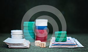 Casino poker chips stack with playing cards, dice and money on green felt background