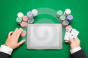 Casino poker player with cards, tablet and chips