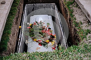 Casket of the dead, with flowers from family and acquittances on the cover