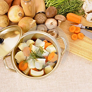 Casserole dish or stockpot with organic vegetables and chopping board on linen tablecloth photo