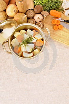 Casserole dish or stockpot with organic vegetables and kitchen chopping board, copy space, vertical photo
