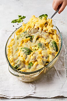 Casserole with pasta, chicken, broccoli and cheese crust in a glass form.