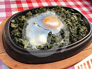 Casserole Spinach with Egg on Red Tablecloth and Wooden Surface.