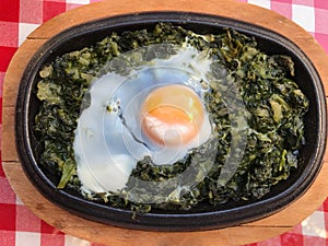 Casserole Spinach with Egg on Red Tablecloth and Wooden Surface.