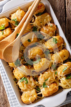 Casserole of Tater Tots with cheese and herbs close up in a baking dish. Vertical top view