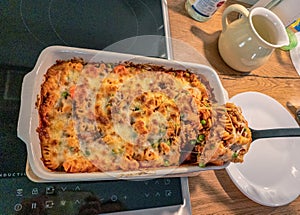 Casserole ziti pasta with with meat, peas, herbs and cheese close-up on a plate. horizontal