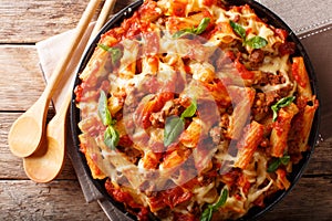 Casserole ziti pasta with minced meat, tomatoes, herbs and cheese close-up. Horizontal top view