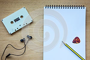Cassette ,headphones and blank notebook on wood for songwriter