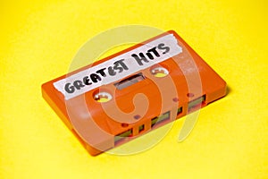 Cassette tape orange on yellow greatest hits