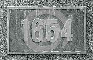 Cast bronze house number on stone wall concept photo. Street exterior metal board plate on wall.