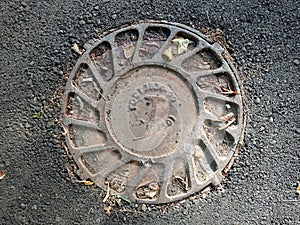 Cast iron cover of the manhole leading to the sewer. On the hatch, the Russian inscription