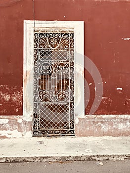 A cast iron door in front of a red facade in Merida - MEXICO