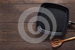 Cast iron frying pan and spatula on the wooden background. Copy