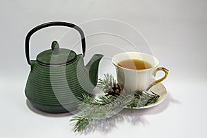 Cast iron green small teapot. White porcelain Cup . White saucer. Christmas tree.