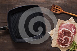 Cast iron griddle pan and beef steak wood on wooden background. Top view, Copy space.