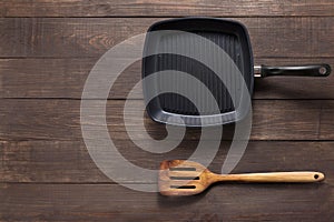 Cast iron griddle pan and turner wood on wooden background