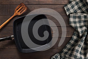 Cast iron griddle pan and turner wood on wooden background. Top view, Copy space.