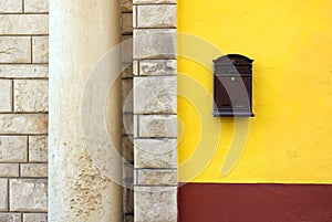 Cast-iron mail slot attached on a yellow wall