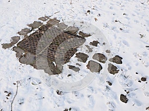 Cast iron man hole cover in winter conditions with light snow cover