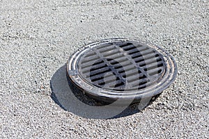 cast iron manhole on limestone pebbles top view on the road. Street Manhole Pavement