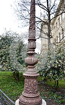 cast iron pillar lighting park path details floral motifs brown shrubs in background green