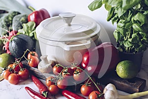 Cast iron pot and vegetables on rustic table. Homemade food, cooking, vegetarian concept