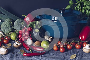 Cast iron pot and vegetables on rustic table. Homemade food, cooking, vegetarian concept