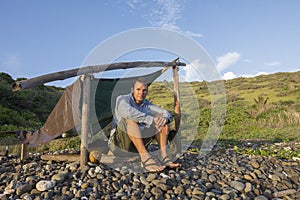 Castaway sitting at simple camp in morning light