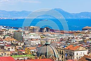 Castel Nuovo towering over neighboring houses in Naples and Bay of Naples, Italy