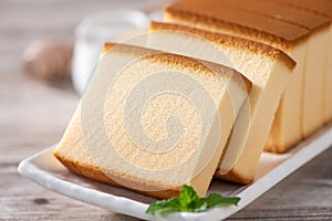 Castella - Delicious Japanese sliced sponge cake food on white plate over rustic wooden table, close up, healthy eating, copy