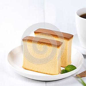 Castella kasutera - Beautiful delicious Japanese sliced sponge cake food on white plate over rustic white wooden table, close up