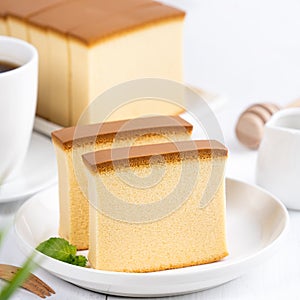 Castella kasutera - Beautiful delicious Japanese sliced sponge cake food on white plate over rustic white wooden table, close up