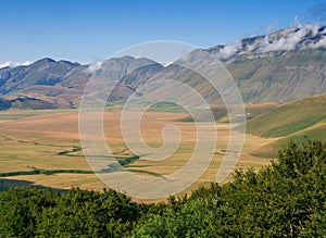 Castelluccio di Norcia, in Umbria, Italy. Fields and hills, Apennines behind, sunny day. Colourful landscape view across