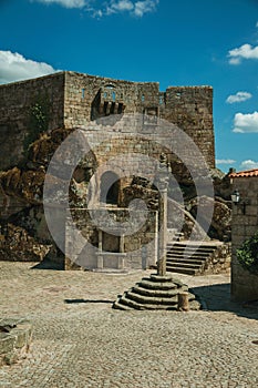 Castle facade over rocky hill on square with pillory