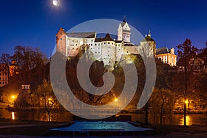 Castle Loket in winter, long night exposure with beautiful blue sky and yellow street christmas city lights with view on river