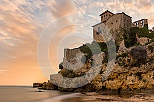 Castle of Tamarit on the rocks surrounded by the sea during the sunset in Altafulla in Spain