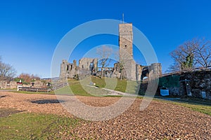 A castle tower and ruins on a hill under a bright blue sky
