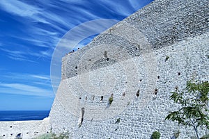 Castle wall in Tremiti islands with a group of people on the top whaching the seascape. For travel and tourism concept