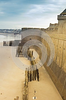 Castle walls of Saint Malo, France, over sea with pilings on the