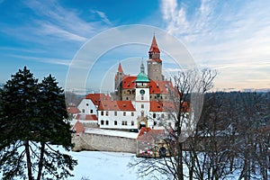 Castle in winter. Romantic fairytale castle in picturesque highland landscape, covered in snow. Castle with white church, high