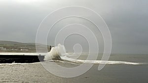Castlerock Northern Ireland. Beautiful ocean wave breaking on the wharf and the lighthouse photo