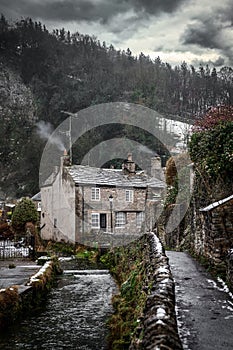 Castleton Beautiful old rural idyllic village cottage with smoke from chimney Peak District river peacefully flowing during winter